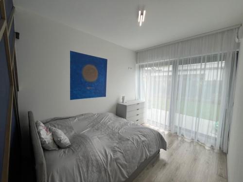 a white bedroom with a bed and a window at Sissy Ring House in Mogyoród