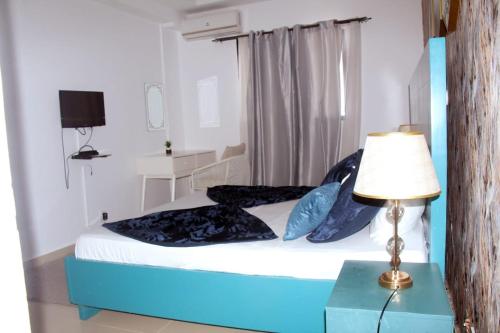 a bedroom with a bed with a lamp and a table at AZURA Skyline in Abidjan