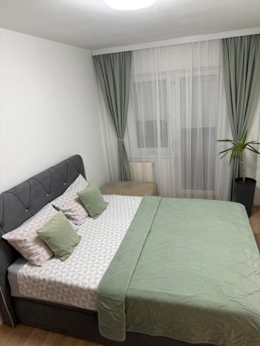 a bedroom with a large bed with green sheets and pillows at Apartman Odmor012-2 in Požarevac