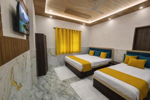 a hotel room with two beds and a tv at H0TEL PARBU KIRPAA Near Premanand Ji Maharaj Mandir Vrindavan in Chhatikara