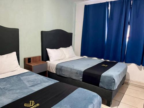 two beds in a room with blue curtains at 4 VENATOR House Boutique in León