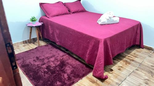 a pink bed with a teddy bear sitting on top of it at Casa da Ana in Tutóia