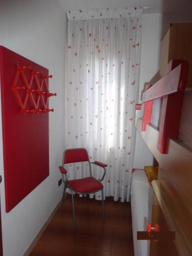 a red chair in a room with a window at Eraclea Mare in Eraclea Mare