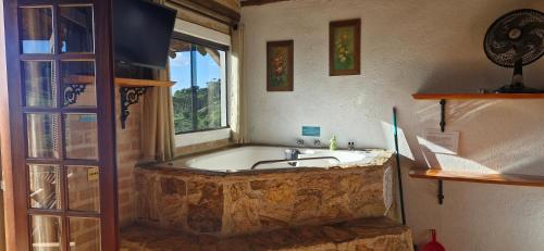 a bathroom with a bath tub with a sink in it at Pousada Chales Rancho Caipira in Santo Antônio do Pinhal