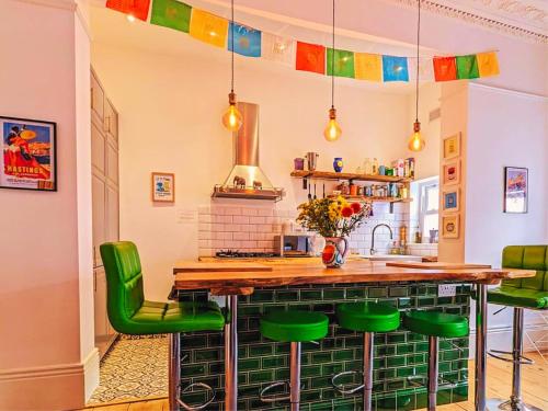 a kitchen with a bar with green bar stools at The Retreat Magnificent Sea Side Apartment in Hastings