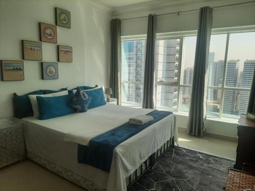 a bedroom with a large bed with blue pillows and windows at Private Room at Expo Centre Sharjah in Sharjah