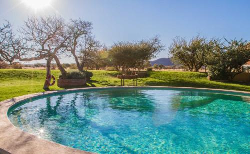 una gran piscina en un patio con árboles en Okonjima Plains Camp en Otjiwarongo