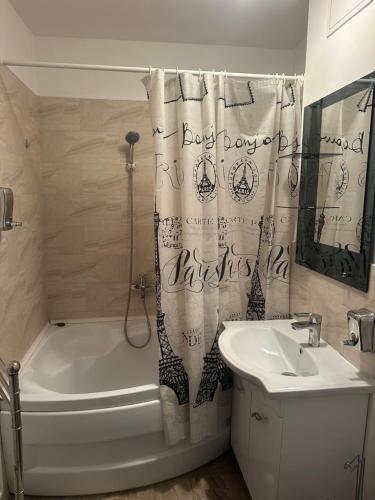 a bathroom with a shower curtain and a sink at Apartament Tudorache Premium in Turceni