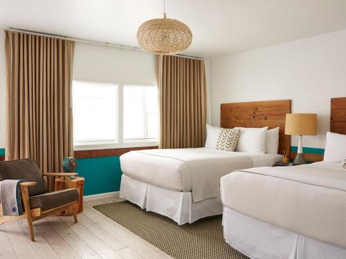 a hotel room with two beds and a chair at Cambria Beach Lodge in Cambria