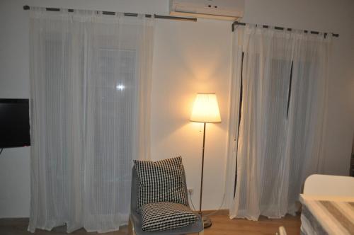 マドリードにあるRonda de Segoviaの白いカーテン、ランプ、椅子が備わる客室です。