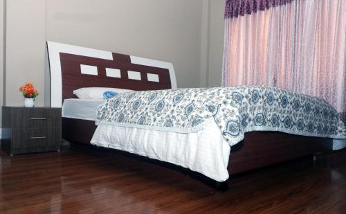 a bedroom with a large bed with a wooden headboard at Pepa's villa and homestay in Khadkagaon