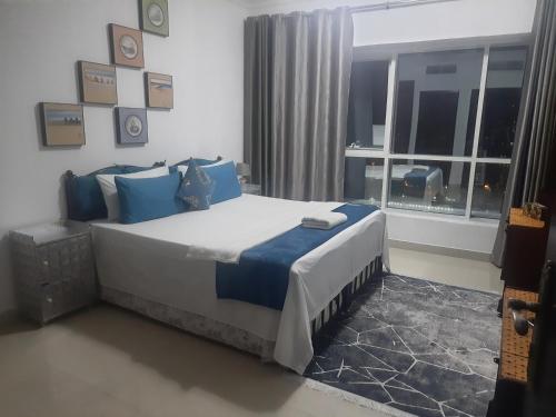 a bedroom with a bed with blue pillows and a window at Private Room at Expo Centre Sharjah in Sharjah