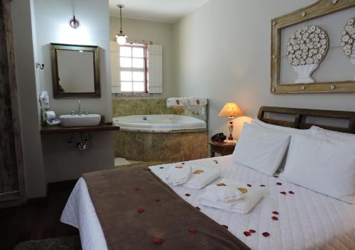 a bedroom with a bed and a bathroom with a tub at Pousada Ouro de Minas in Tiradentes