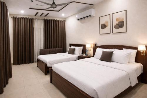 a hotel room with two beds and a table at Al Huda Hotel in Multan