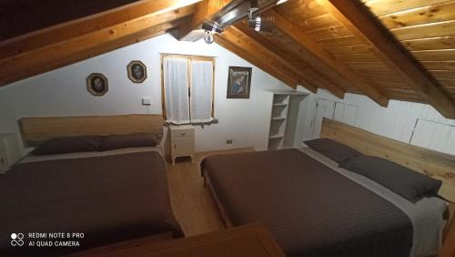 two beds in a room with wooden ceilings at Il BORGO DEL VENTASSO in Busana