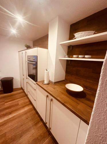 a kitchen with white cabinets and a wooden floor at Ferienhaus Griede mit 3 Schlafzimmern in Mörsdorf