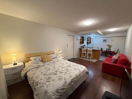 a bedroom with a bed and a red couch at Lovely suite in Burnaby