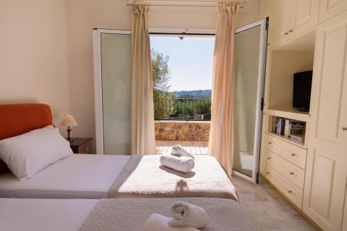 a bedroom with a bed and a large window at Villa Odyssey Verde in Dassia