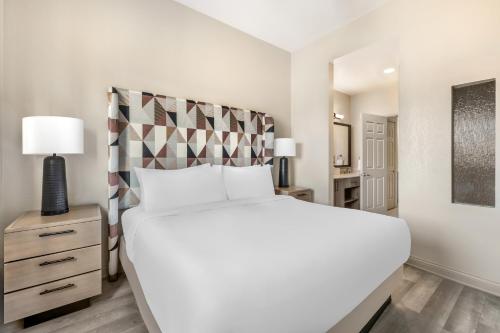 a white bedroom with a large bed and a nightstand at Bluegreen Vacations Club 36, an Ascend Collection Resort in Las Vegas