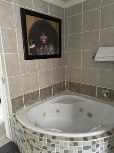 a bathroom with a bath tub with a picture on the wall at Virginia Town House in Mthatha