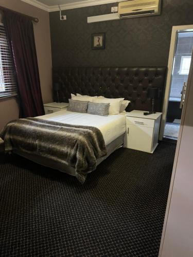 a bedroom with a large bed with a leather headboard at Virginia Town House in Mthatha