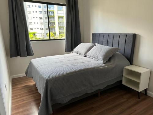 a bed in a bedroom with a window at Apto vista in Ponta Grossa