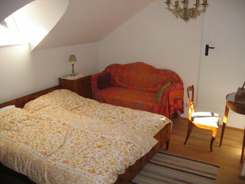 a bedroom with two beds and a chair and a couch at Rosenvilla - Musikerschlössl in Bad Ischl
