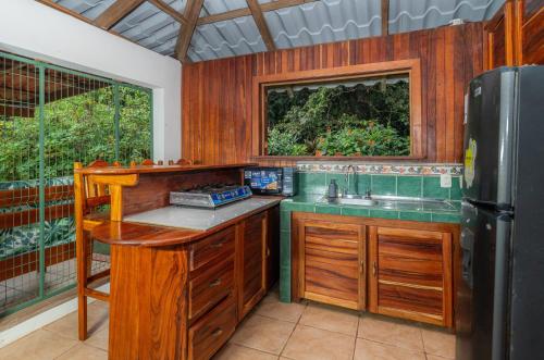 a kitchen with wooden cabinets and a sink and a refrigerator at Corcovado Green Cabin & House in Drake