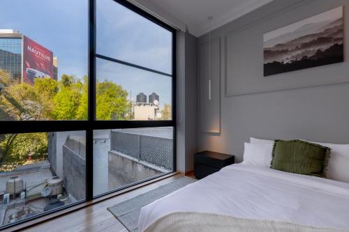 a bedroom with a bed and a large window at Capitalia Temistocles Polanco in Mexico City