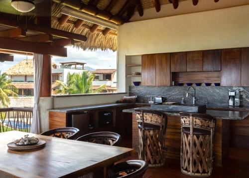 an outdoor kitchen with wooden cabinets and wooden tables and chairs at Stunning, Oceanfront Casa de Olas in Ixtapa-Zihuatanejo International