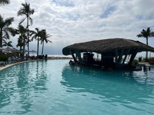 a large swimming pool with a straw hut at luxury 2bed condo in Nuevo Vallarta