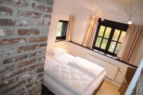 デュルビュイにあるHoliday Home Poppenhuisのレンガの壁と白いベッドが備わる客室です。