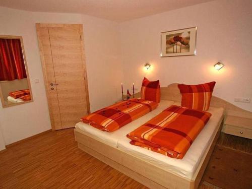 a bedroom with two beds with orange and orange striped pillows at Apartment Künzel by Interhome in Schröcken