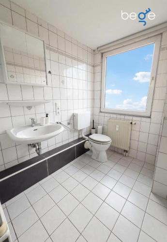 a bathroom with a toilet and a sink and a window at BEGE APARTMENTS FlowLoft in Wegberg