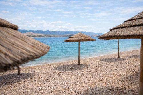 three straw umbrellas on a beach near the water at LUXURY MANDRE HOUSE in Mandre