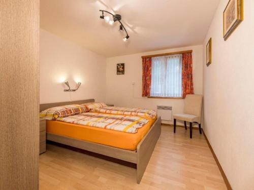 a bedroom with a bed and a chair and a window at Apartment Wohnung Muntegn by Interhome in Vicosoprano