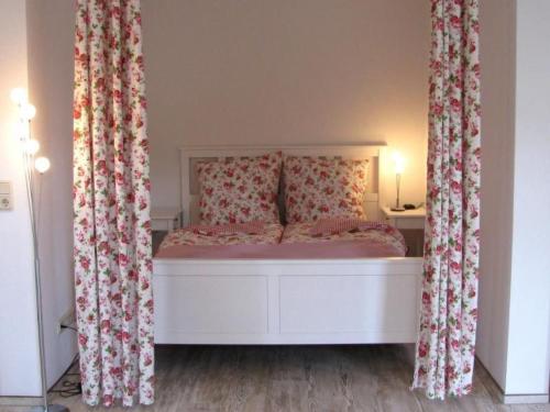 a bedroom with a white bed with floral curtains at Apartment Florö by Interhome in Putbus
