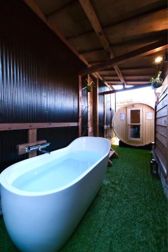a large bath tub in a bathroom with green carpet at 城ヶ島 浦ノ間邸 デザイナーズ古民家サウナヴィラ 富士山ビューBBqテラス付 in Miura