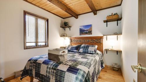 a bedroom with a bed with a blanket and a window at Chalet All Day by AvantStay in Arrowhead Lake