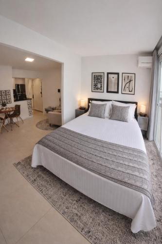 a bedroom with a large white bed and a living room at Studio 929 Gold Star 400m Ferry to Rio 1Gb Wi-Fi in Niterói