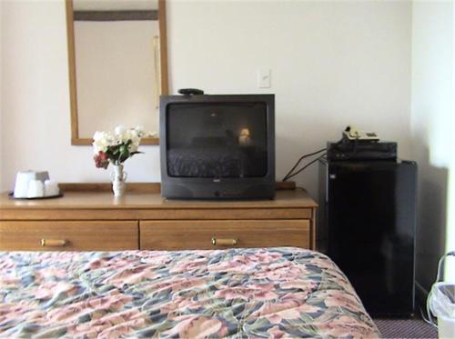 a bedroom with a tv on a dresser with a bed at Valley Motel Pittsburgh in Harmarville