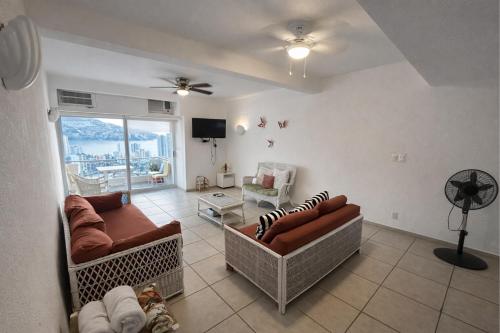 a living room with two couches and a tv at Bella Brisas Stays in Acapulco