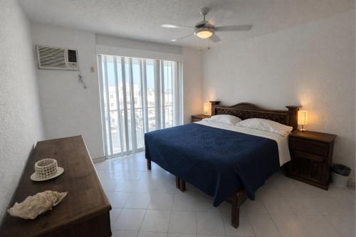 a bedroom with a bed with a blue blanket and a table at Bella Brisas Stays in Acapulco