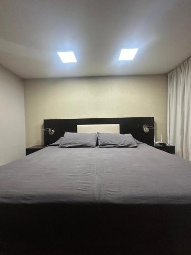 a large bed in a bedroom with two lights at Urban III - Cómodo monoambiente en pleno centro in San Juan