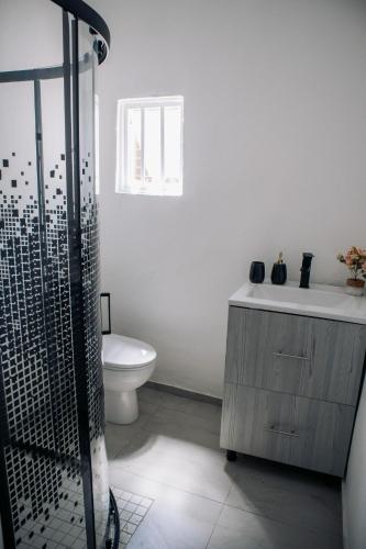 a bathroom with a toilet and a sink and a shower at La Grande in Benoni