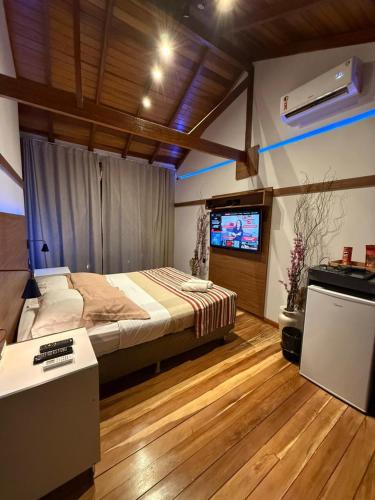 a bedroom with a bed and a flat screen tv at Deck1920 by Estadias Incríveis in Cascavel