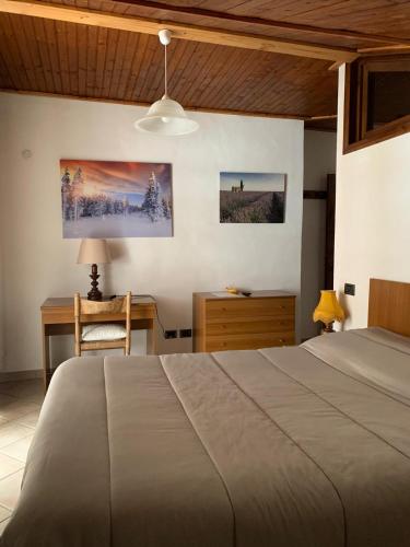 a bedroom with a bed and a desk with a lamp at Albergo Martinet in Vernante