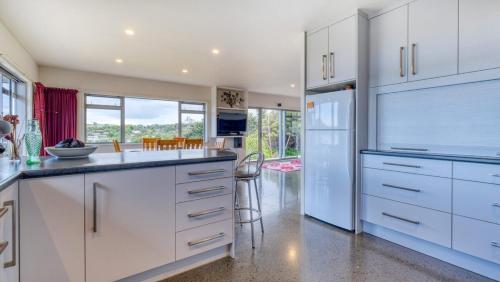 a kitchen with white cabinets and a white refrigerator at Hook'em Heights in Pukenui