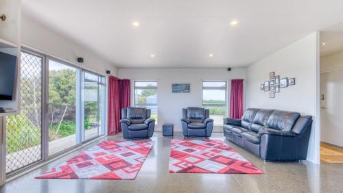 a living room with two leather chairs and a television at Hook'em Heights in Pukenui