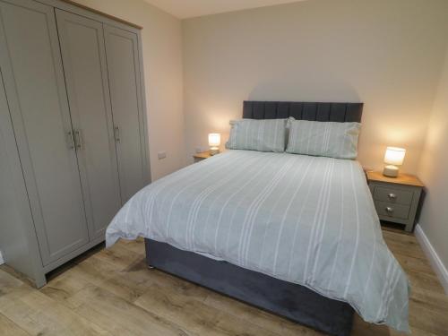 a bedroom with a large white bed with two lamps at Binevenagh Point Cabin in Limavady